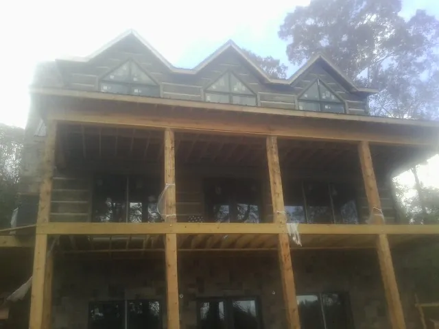 Dormers and porch framing on a large log home under construction — Roof Coating work by our crew in Arnaudville