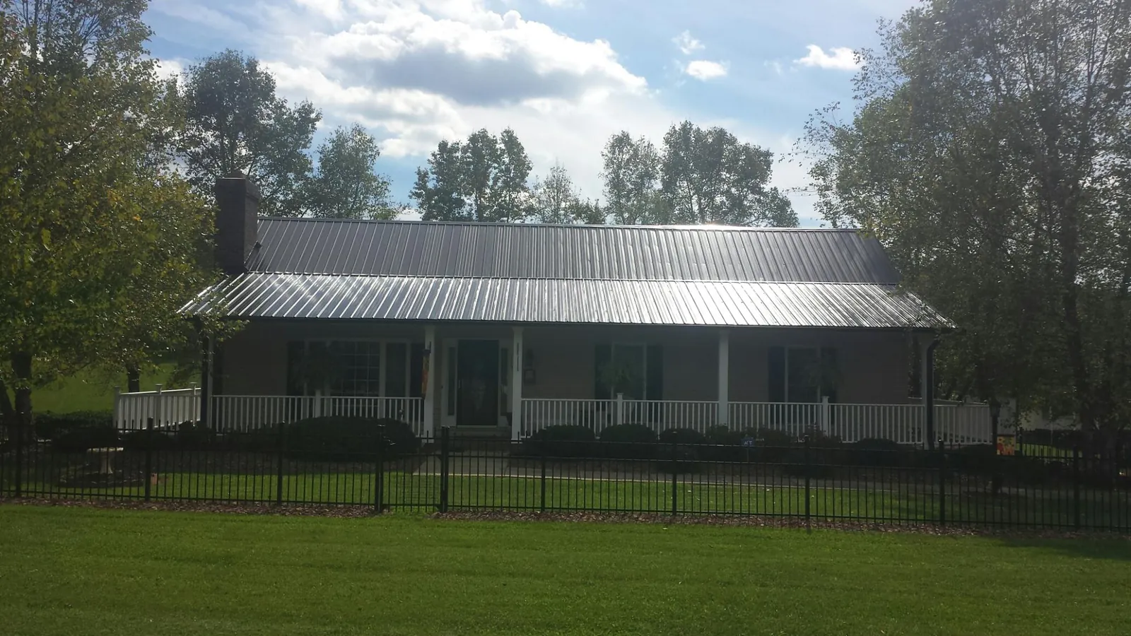 Gray metal roof on a brick ranch with a full width front porch — Gutter Guard Installation work by our crew in Arnaudville
