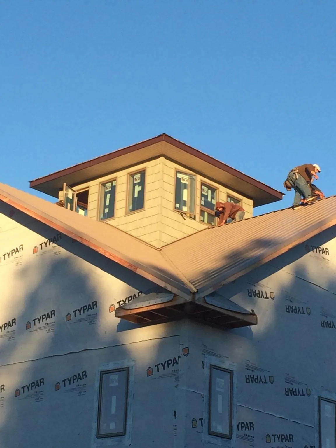 Roofers working around a rooftop cupola on a new metal roof at sunset — Roof Waterproofing in Arnaudville by Roofing Brothers